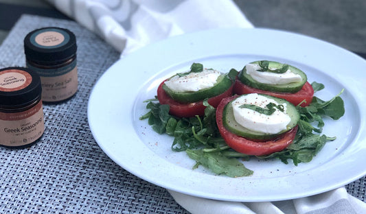 Garden salad with sliced tomato, cucumber, fresh mozzarella and basil on arugula