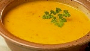 Bowl of creamy curried lentil and sweet potato soup with toasted coconut