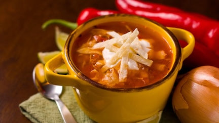 Bowl of Mexican tortilla soup with chicken, black beans and tortilla strips